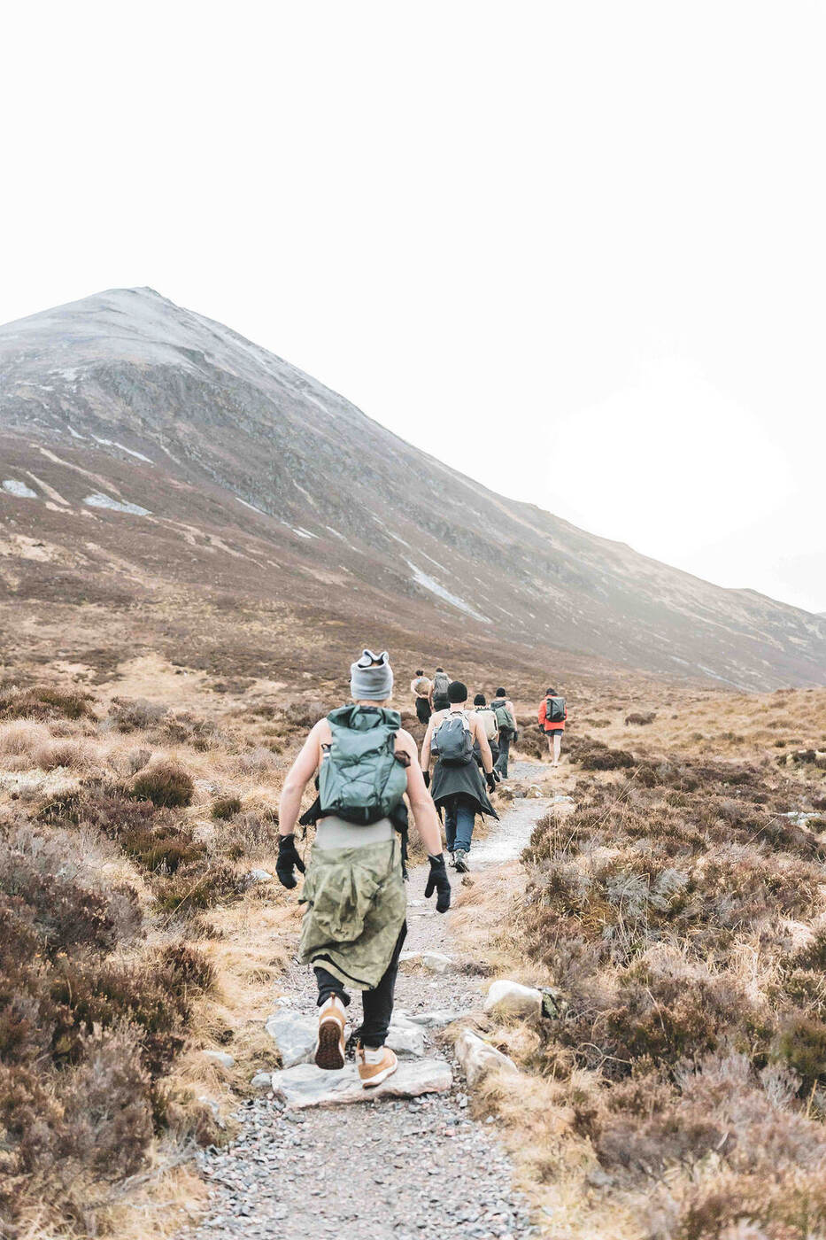 Grupo a caminhar de costas por uma trilha nas Highlands escocesas